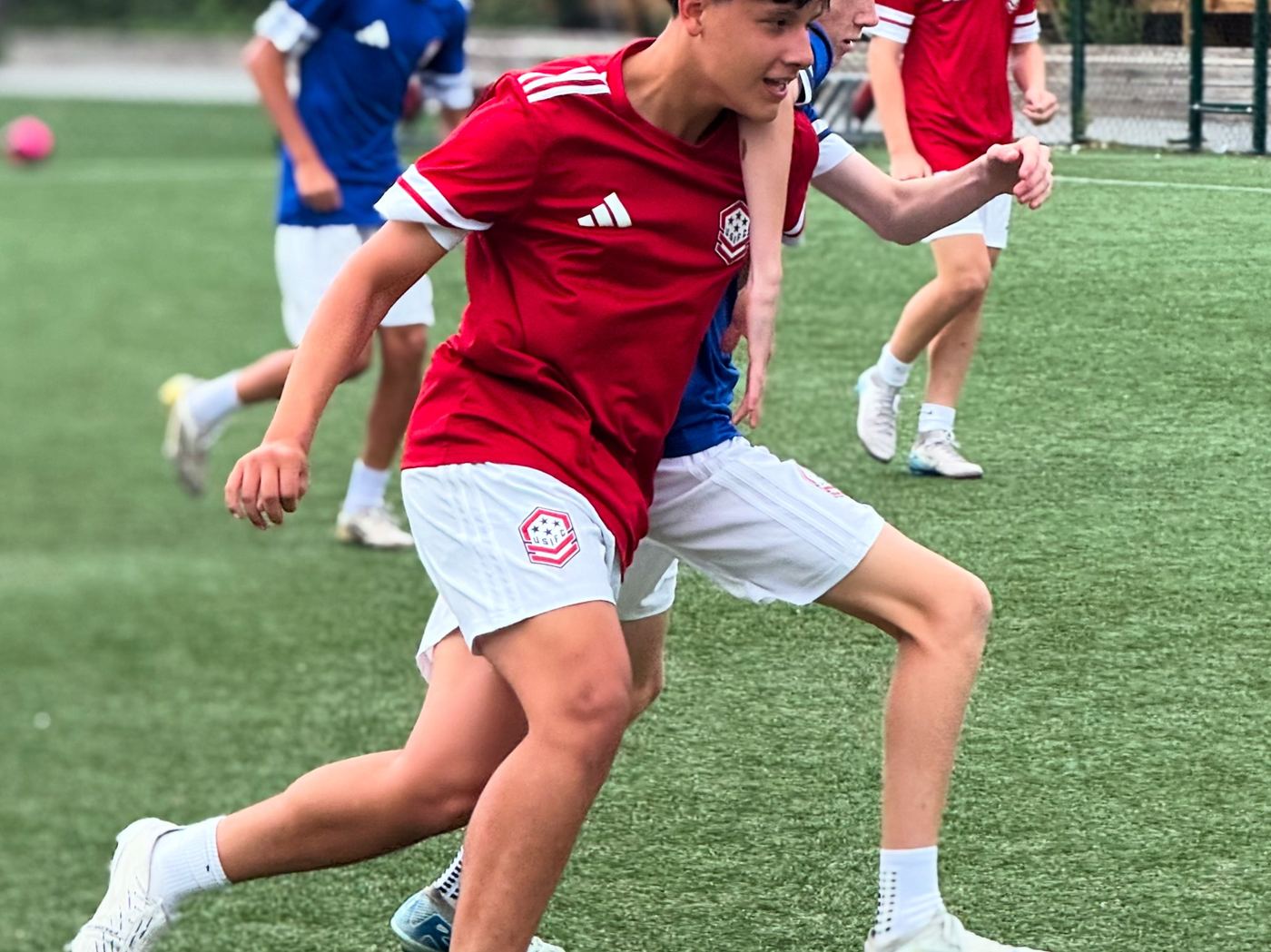 A USIFC player in red drives past a defender during a friendly